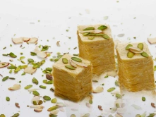 Best Soan Papdi Sweet Manufacturers Latest Price in Chennai Three slices of cake topped with nuts create a delightful dessert presentation on a plate.