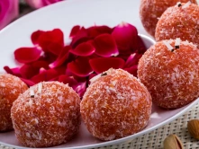 Best Authentic Indian Sweets For Diwali Celebration Decorative plate of Badam Rose Laddu, featuring golden sweets garnished with vibrant rose petals.