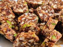 Best Delicious South Indian Nuts Burfi Sweet Shop in Chennai An elegantly arranged plate of best nuts-burfi sweet and assorted nuts sits on a wooden table.
