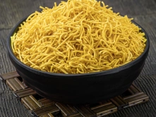 Best South Indian Omapodi Sweet Suppliers in Chennai A bowl of yellow noodles topped with omapodi graces an appetizing and inviting rustic table.